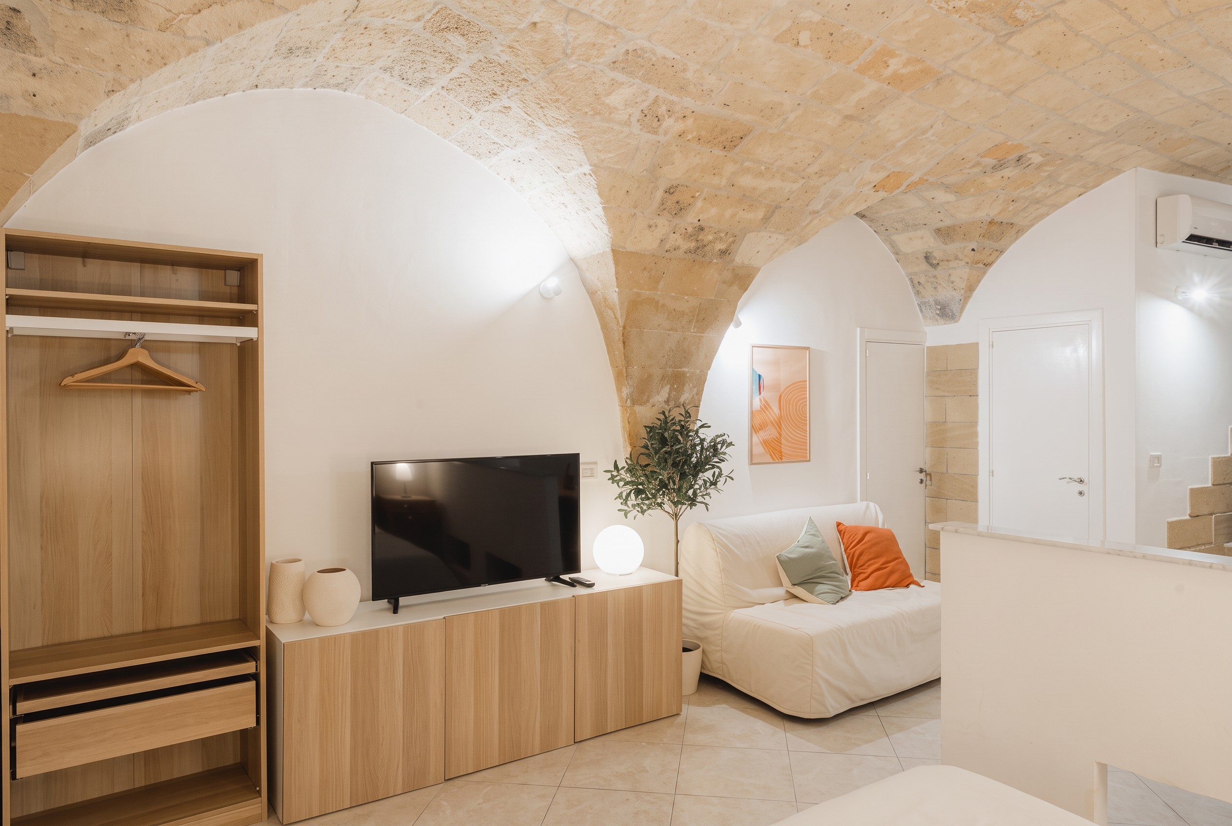 Lounge area with sofa and television beneath a vaulted ceiling