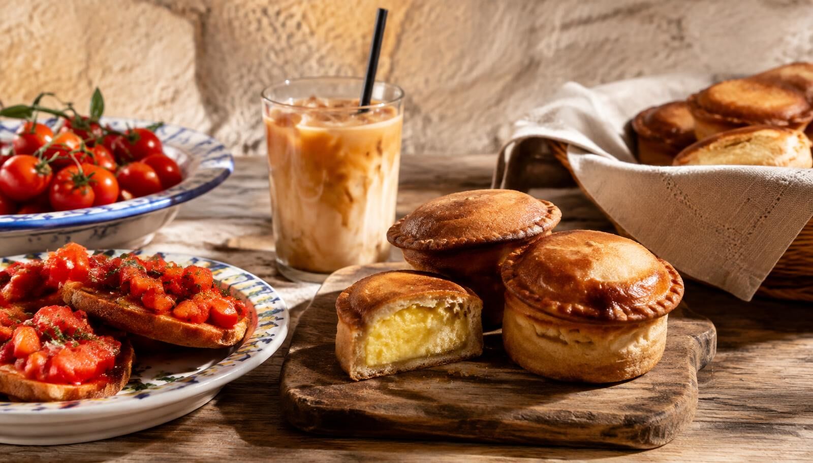 Une table en pierre avec un café en glace, un pasticciotto chaud et une frisa garnie de tomates fraîches.